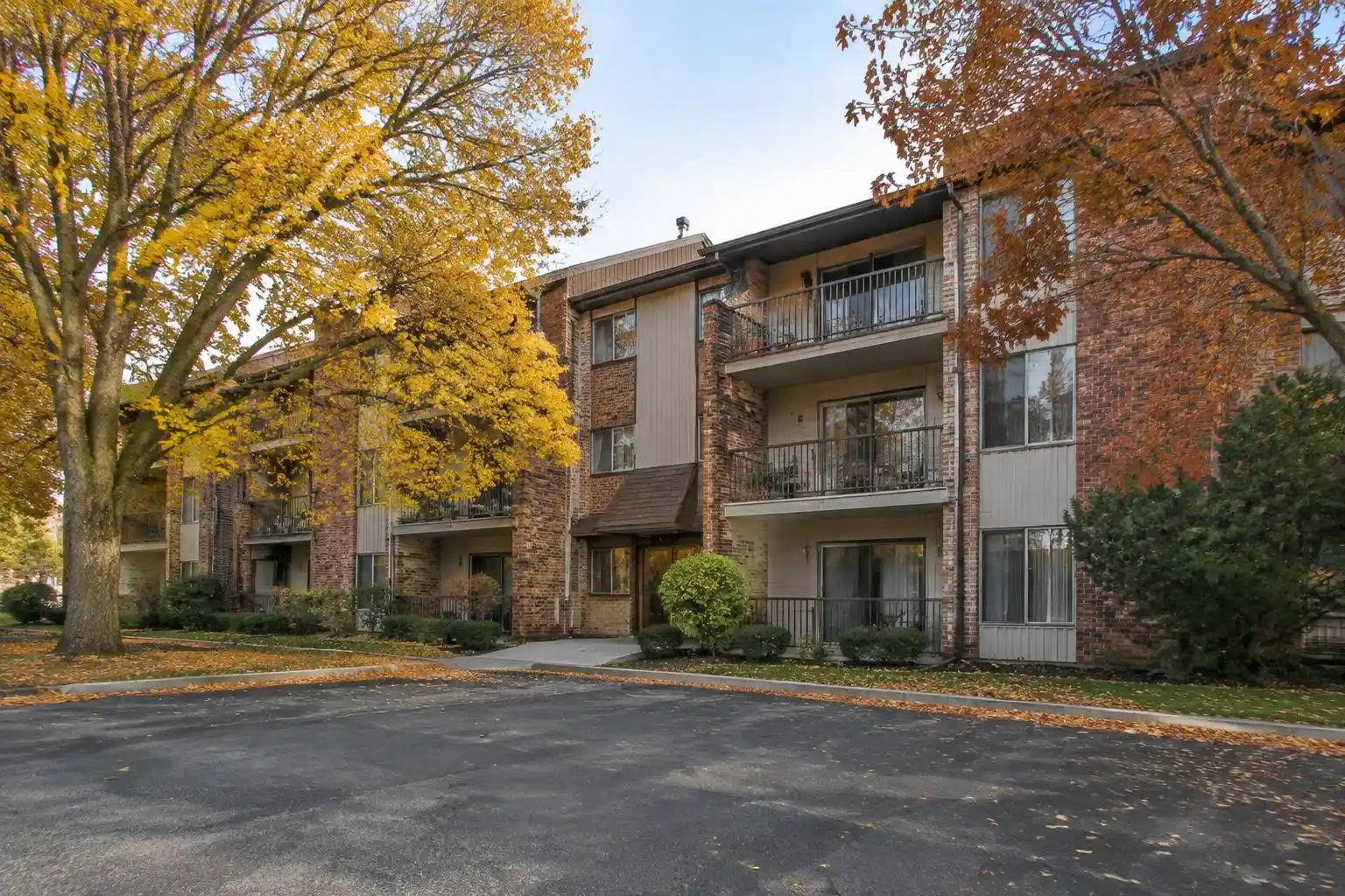 Three-story brick condo building with balconies and mature trees in Palatine, IL